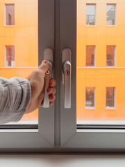 Personal perspective male closing opening modern pvc aluminum triple window with multiple windows of the adjacent building - insulation of the house