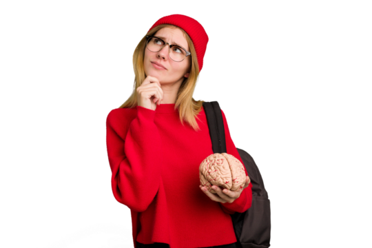 Young caucasian student woman holding a brain isolated looking sideways with doubtful and skeptical expression.