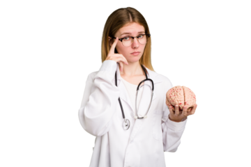 Young doctor caucasian woman holding a brain isolated pointing temple with finger, thinking, focused on a task.