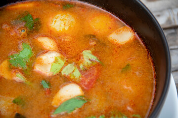 Top view of tom yam seafood soup in black bowl