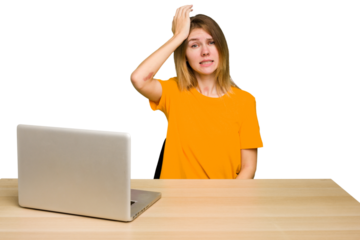 Young caucasian woman in a workplace working with a laptop isolated forgetting something, slapping forehead with palm and closing eyes.