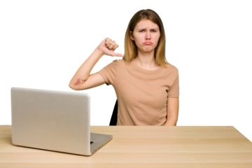 Young caucasian woman in a workplace working with a laptop isolated showing a dislike gesture, thumbs down. Disagreement concept.