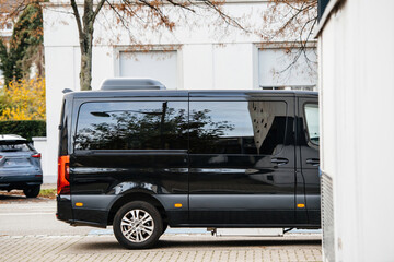 Rear view of black executive luxury van parked in city - lateral entrance door