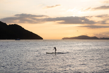 Girl practicing stand up paddle during the late afternoon in Santos bay