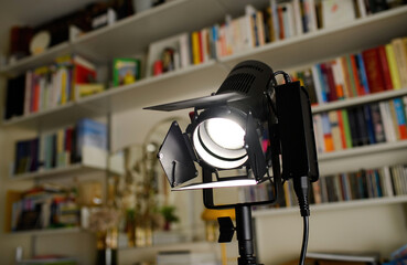 Professional photographer videographer strobe light in living room with multiple shelves with books in background