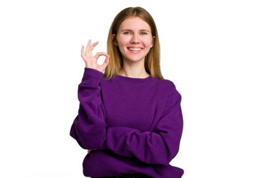 Young caucasian woman isolated winks an eye and holds an okay gesture with hand.
