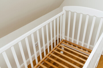 View from above of new new crib without mattress in nursery room - relocation baby arrival preparation concept