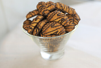 chocolate cookies in a transparent vase on a light background. place for text