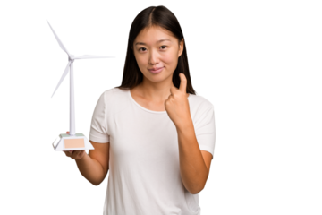 Young asian woman holding a small wind energy mill isolated pointing with finger at you as if inviting come closer.