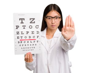 Young asian oculist woman holding a eye chart paper isolated standing with outstretched hand showing stop sign, preventing you.