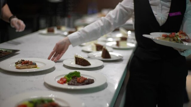 Close-up cropped shot of unrecognizable female waiter collecting plates of ready meals and taking them out into restaurant guest lounge. Shooting in slow motion.