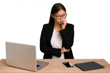 Young business asian woman sitting on a table isolated who feels sad and pensive, looking at copy space.