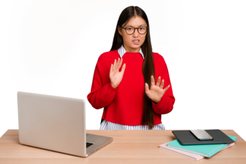 Young student asian woman in a workplace with a laptop isolated rejecting someone showing a gesture of disgust.