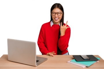 Young student asian woman in a workplace with a laptop isolated showing rock gesture with fingers