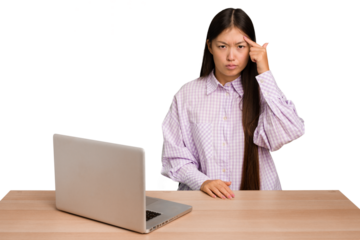 Young student asian woman in a workplace with a laptop isolated pointing temple with finger, thinking, focused on a task.