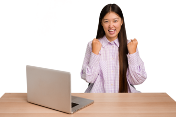 Young student asian woman in a workplace with a laptop isolated cheering carefree and excited. Victory concept.
