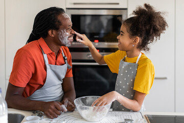 Fototapeta premium Cheerful Black Dad And Daughter Playing With Floor While Baking In Kitchen