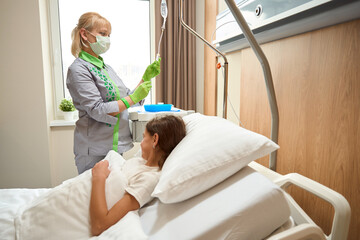 Nurse corrects the dropper and communicates with a small patient