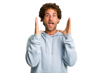 Young curly smart caucasian man cut out isolated celebrating a victory or success, he is surprised and shocked.