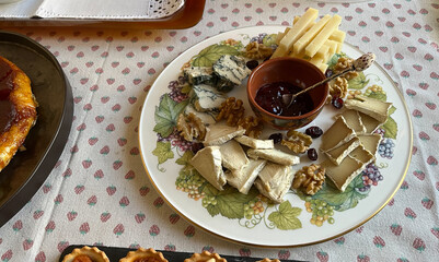 Exquisite plate with vegan cheeses with walnuts and sauce on tablecloth in kitchen