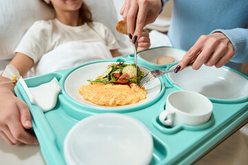 Obraz na płótnie Canvas Woman feeds breakfast to a girl on a hospital bed