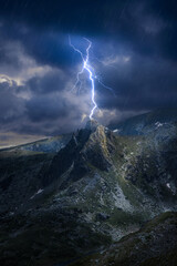Lightning strikes a mountain top in dark stormy weather night. electricity strike on a mountain peak summit