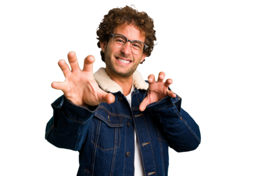 Young curly smart caucasian man cut out isolated showing claws imitating a cat, aggressive gesture.
