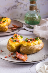 Twice baked potatoes with bacon and cheese on a plate on the table. Homemade dinner. Vertical view
