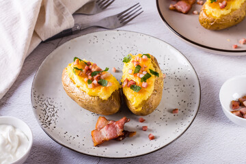 Homemade twice baked potatoes with cheese and bacon on a plate on the table.