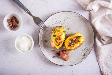 Twice baked potatoes with bacon and cheese on a plate on the table. Homemade dinner. Top view