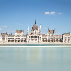 Hungarian parliament building on Danube, Budapest, long exposure square, clear blue sky, blurred water 