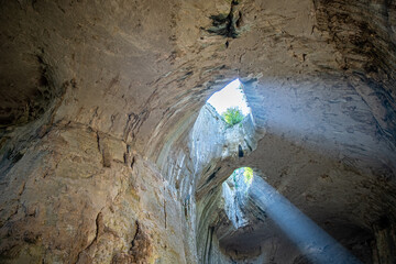 Cave ceiling overhang with holes and light rays beams coming through