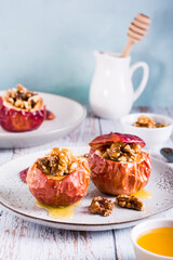 Whole baked apples with honey and walnuts on a plate. Homemade dessert. Vertical view