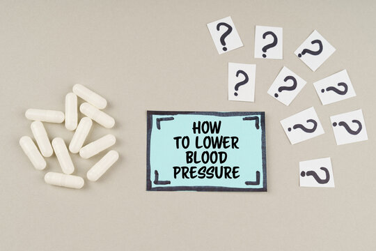 On a gray surface there are question marks and a blue sticker with the inscription - How to lower blood pressure