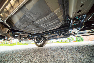 View of the car by auto mechanic from below. Automobile exhaust system and hoses. All wheel drive...