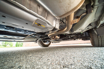 View of the car by auto mechanic from below. Automobile exhaust system and hoses. All wheel drive...