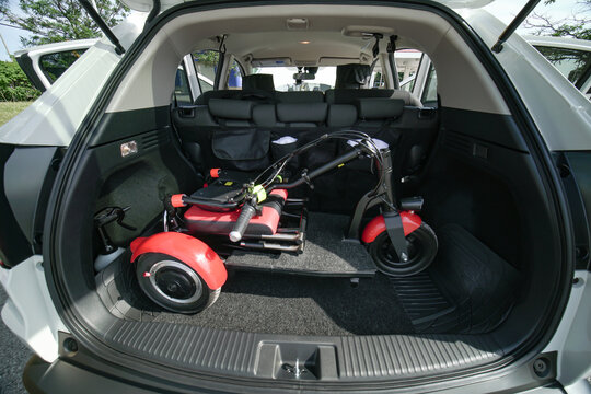 Electric Wheelchair Or Foldable Three Wheels Mobility Scooter In The Car Trunk. Mobility Means For People With Disability Or Mobility Issues. Freedom Of Movement And Daily Life Independence.