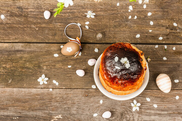 Traditional Easter cake in a rustic style. Vintage baking pot, blooming cherry plum branches. Wooden background