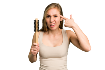 Young caucasian woman using an hair comb isolated showing a disappointment gesture with forefinger.