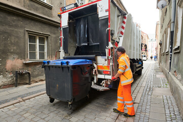 garbage and waste removal services. Worker loading waste bin into truck at city