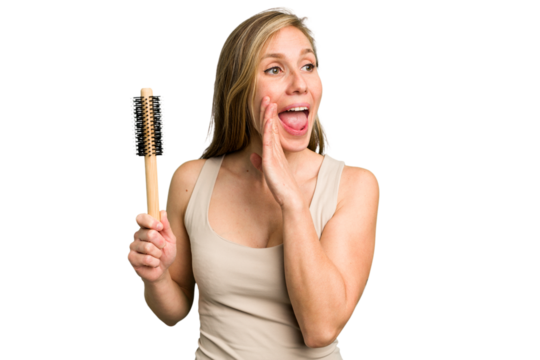 Young caucasian woman using an hair comb isolated shouting and holding palm near opened mouth.