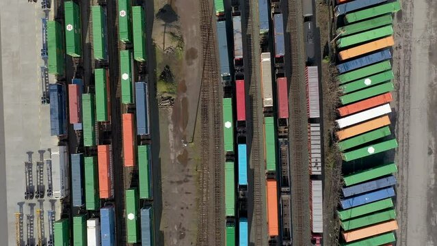 Aerial top down perspective flight over shipping containers at a railroad yard.