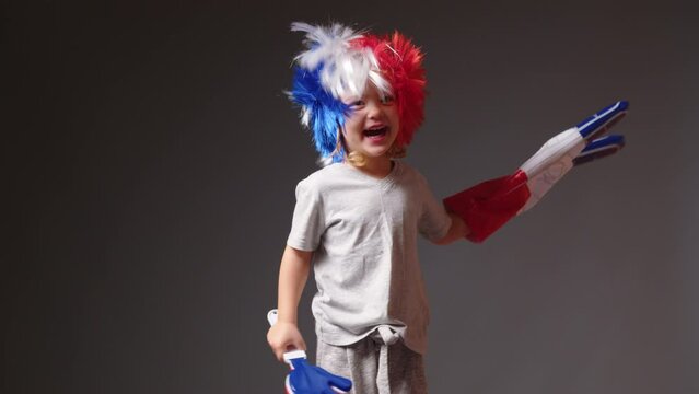 Young girl with a mohawk on his head in the color of the French flag supports his sports team. Football fan baby at the stadium rejoices at the victory of his team