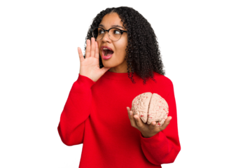 Young african american woman holding a brain model isolated shouting and holding palm near opened mouth.