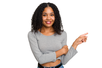 Young african american woman with curly hair cut out isolated smiling cheerfully pointing with forefinger away.