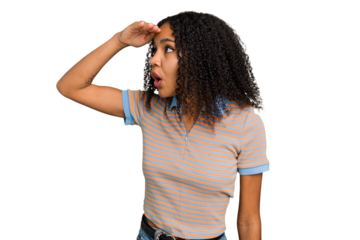 Young african american woman with curly hair cut out isolated looking far away keeping hand on forehead.