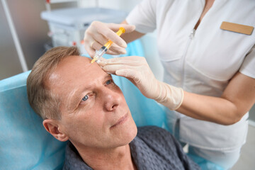 Fair-haired gentleman having facial skin treatment with plasma injection