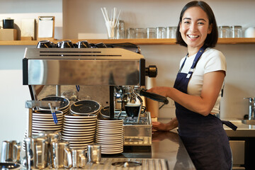 Happy smiling bartender, barista using coffee machine, prepare order, making cappuccino or latte,...