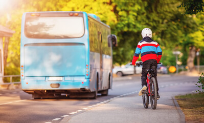 Boy on a bicycle trying to catch up with a blue bus.