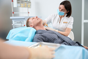 Aging gentleman having great skin treatment by injection at clinic